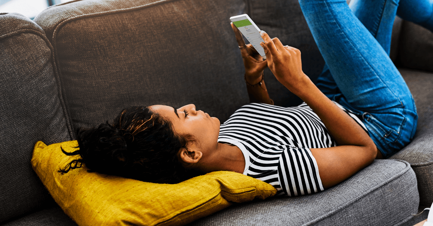 12 Budgeting Tips to Help You Win With Money Woman laying on couch budgeting with budget app