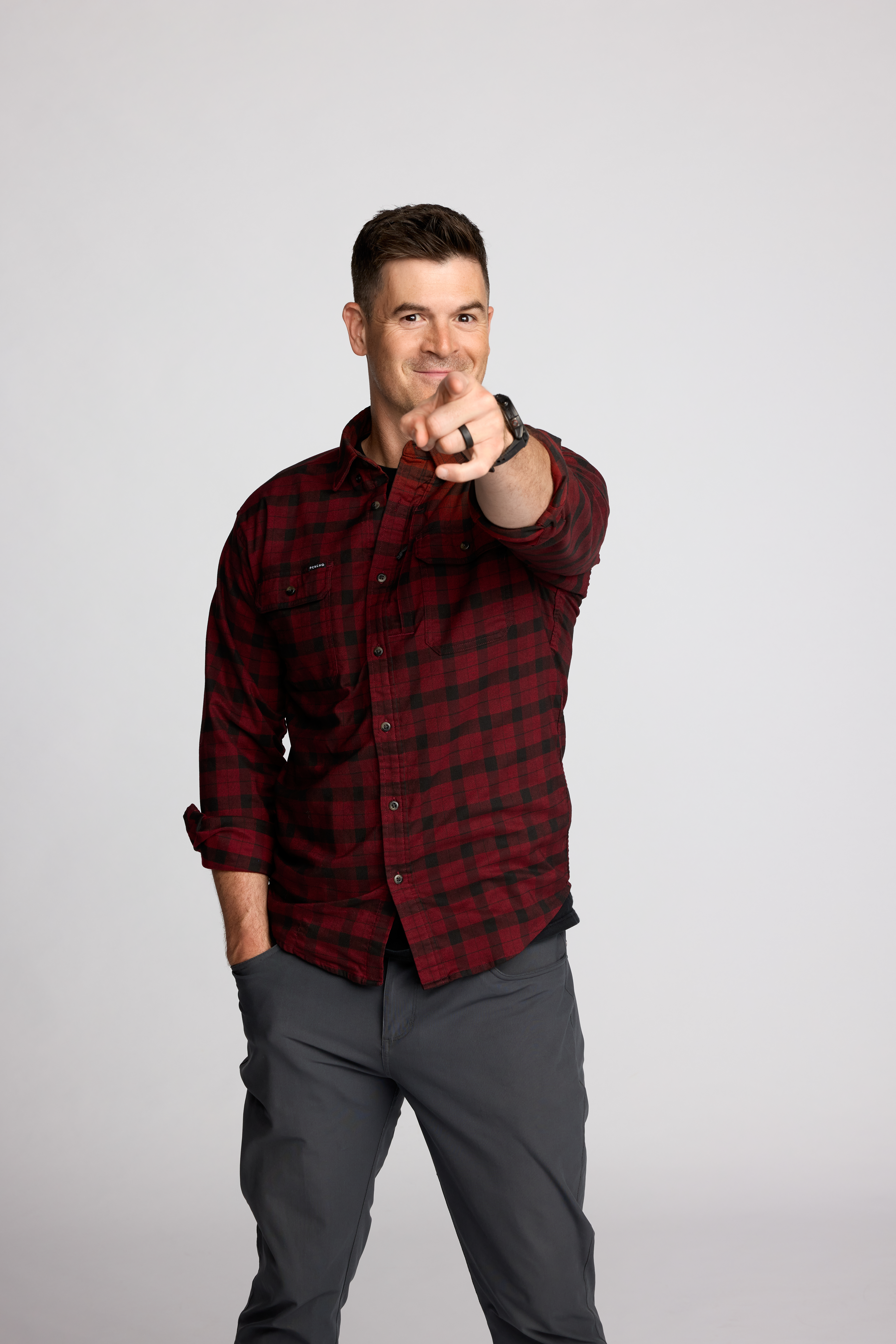 casual portrait of Dr. John Delony point at the camera wearing a red plaid shirt