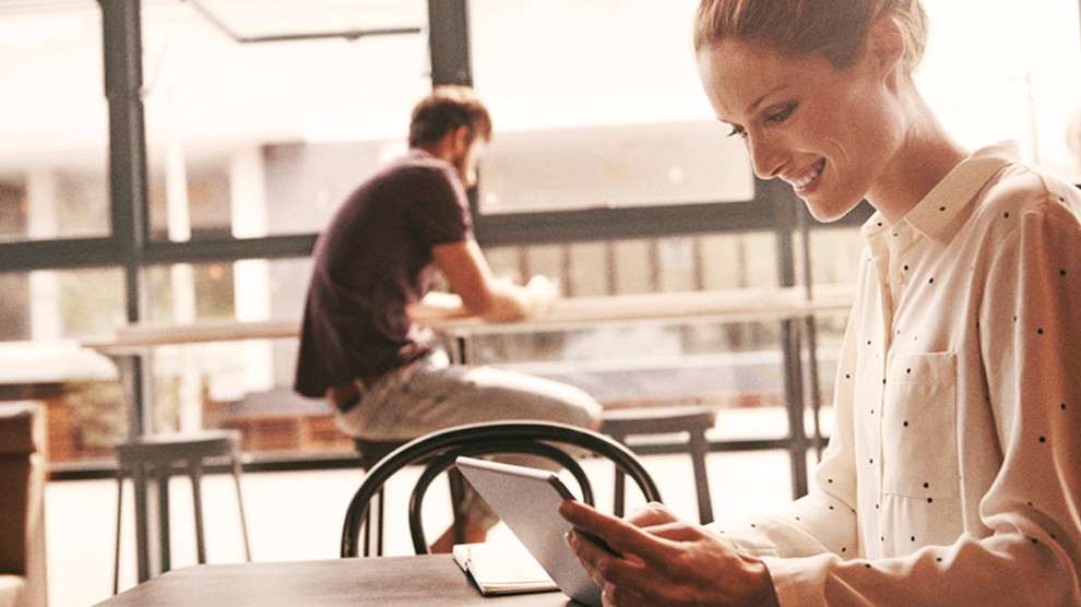 A woman in a coffee shop works on a tablet